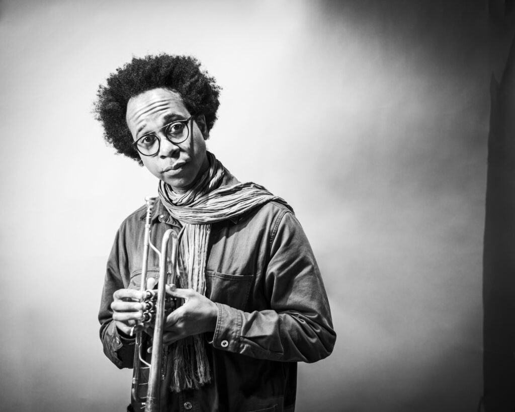 Porträt eines schwarzen Jazzmusikers mit Brille und Sobran, schwarz-weiß, kreative Studioaufnahme vor neutralem Hintergrund.