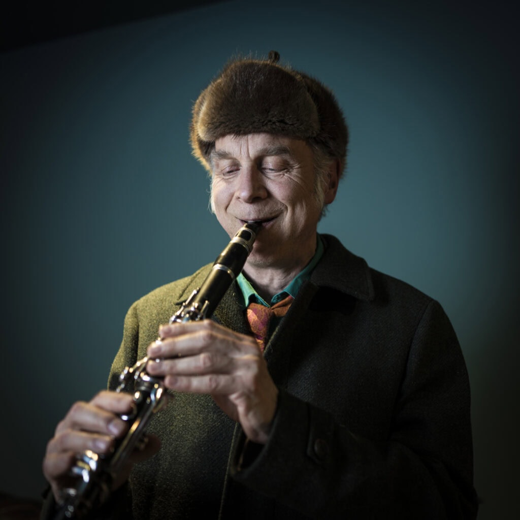 Gemütliches Portrait eines Mannes mit Mütze, der auf einem Saxophon spielt und dabei lächelt, im Stil von Frank Siemers Fotografien aus Hamburg.