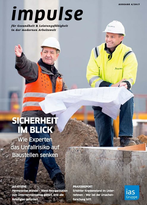 Hohe Sichtbarkeit eines Bauprojekts mit zwei Männern in Sicherheitskleidung, die über Bauplänen stehen.