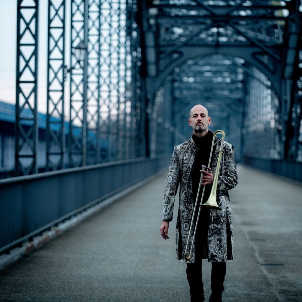 Feuriger Bogen-Brücke mit einem Mann im Vordergrund, der eine Trompete hält, in Hamburg, künstlerische Schwarz-Weiß-Analogaufnahme.